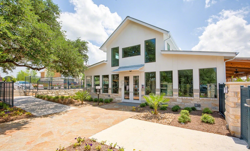 A white house with a black fence and a tree in front.