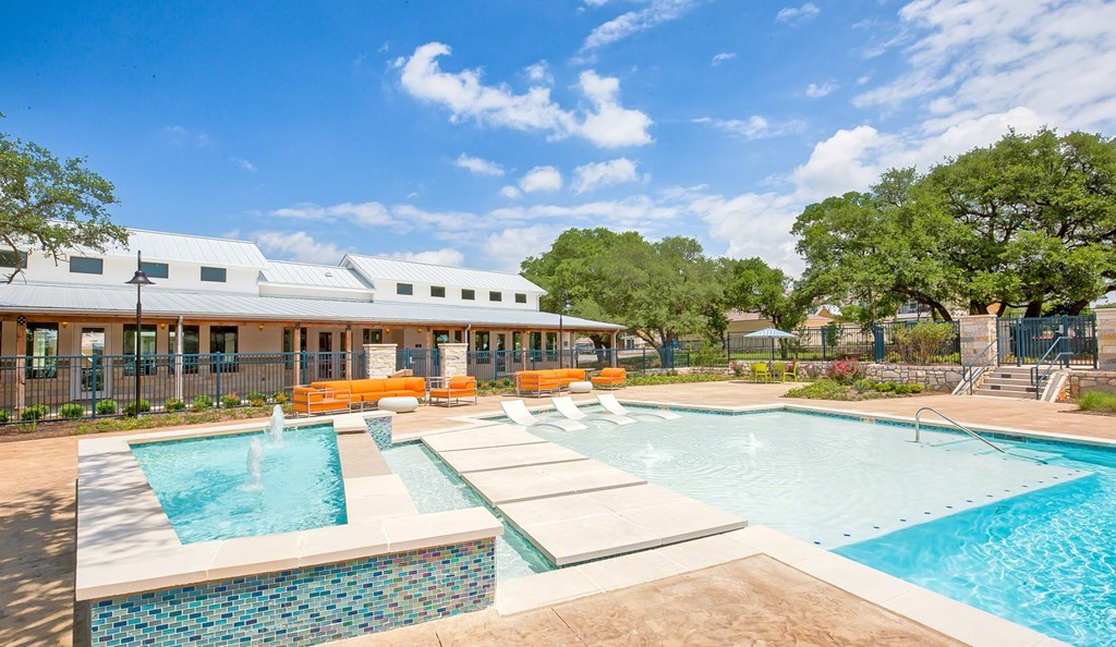 A swimming pool with a waterfall and a building in the background.