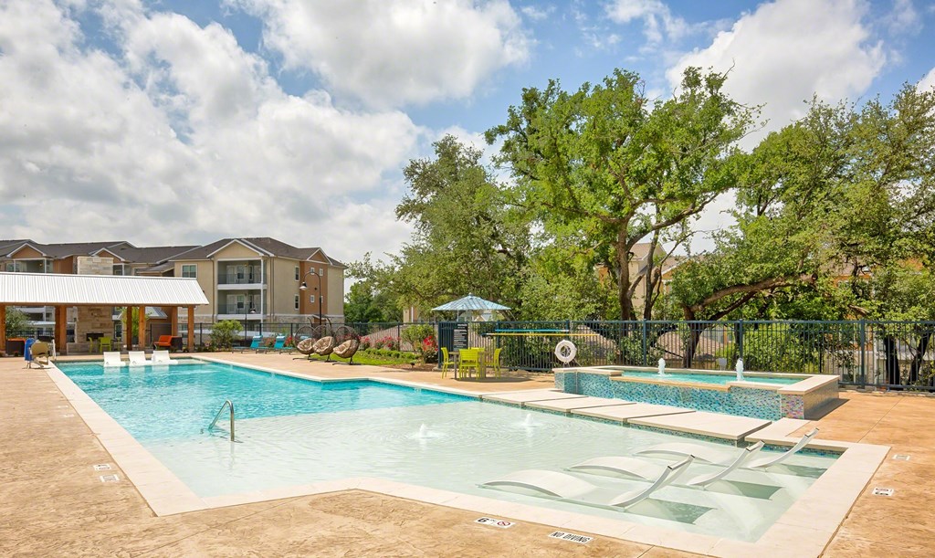 A large outdoor swimming pool with a slide and a fence.