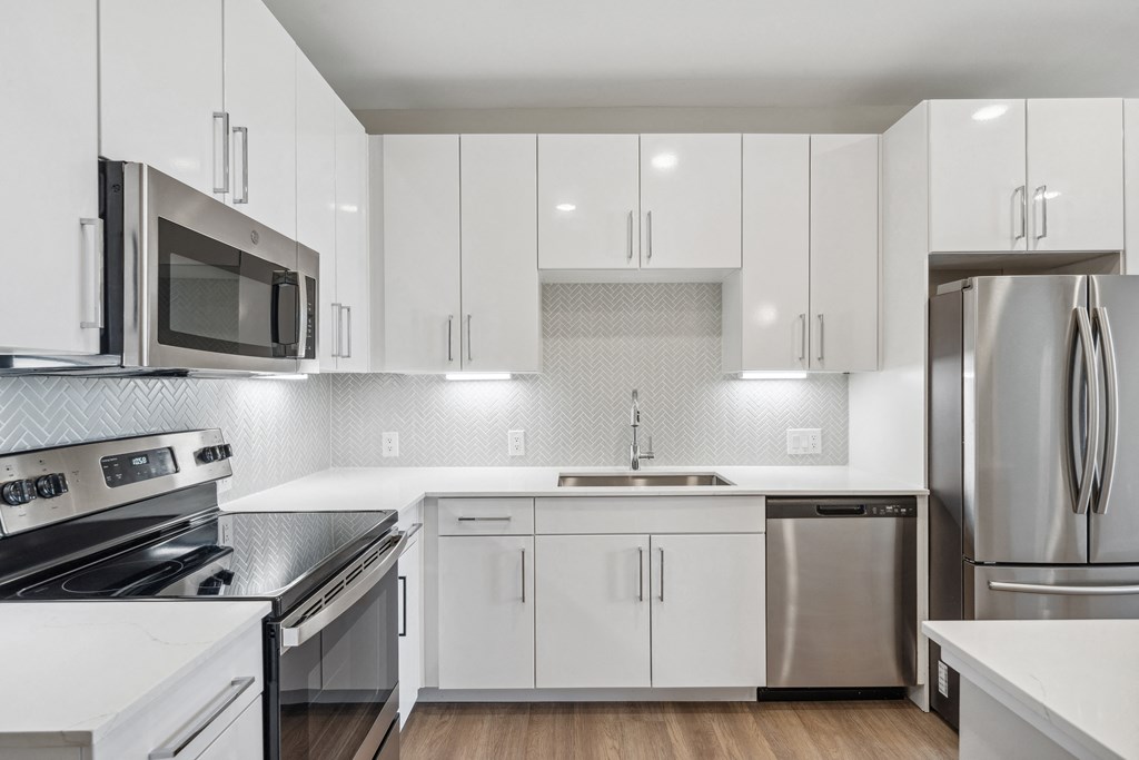 an all white kitchen with stainless steel appliances and white cabinets