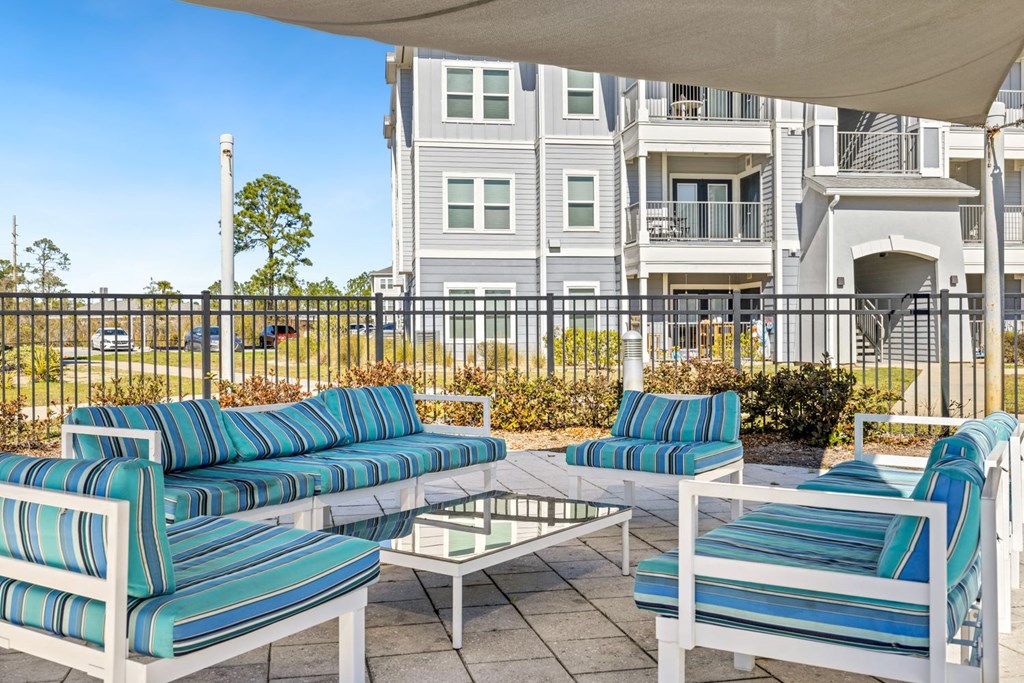 A patio with a white table and blue and green striped chairs.