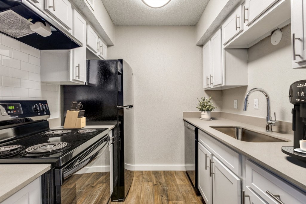 a kitchen with white cabinets and black appliances and a sink