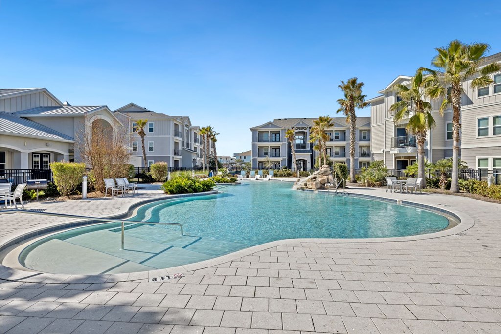 A swimming pool surrounded by a brick patio and palm trees.