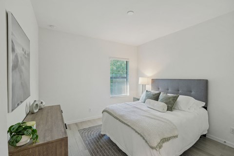 A bedroom with a large bed and a painting on the wall.