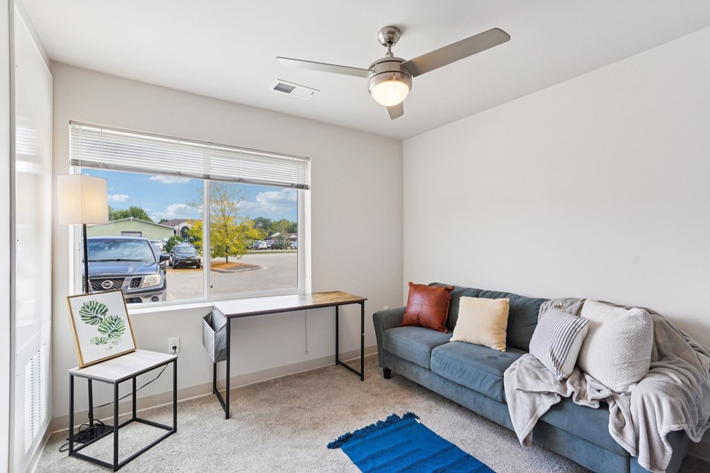 A living room with a grey couch and a ceiling fan.