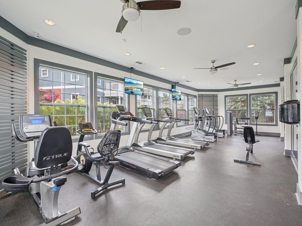 A gym with treadmills, exercise bikes, and a television.