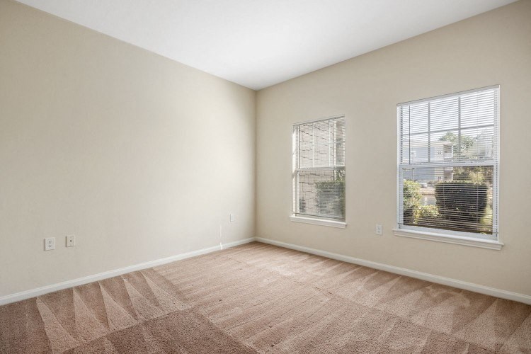 the living room of an empty home with two windows