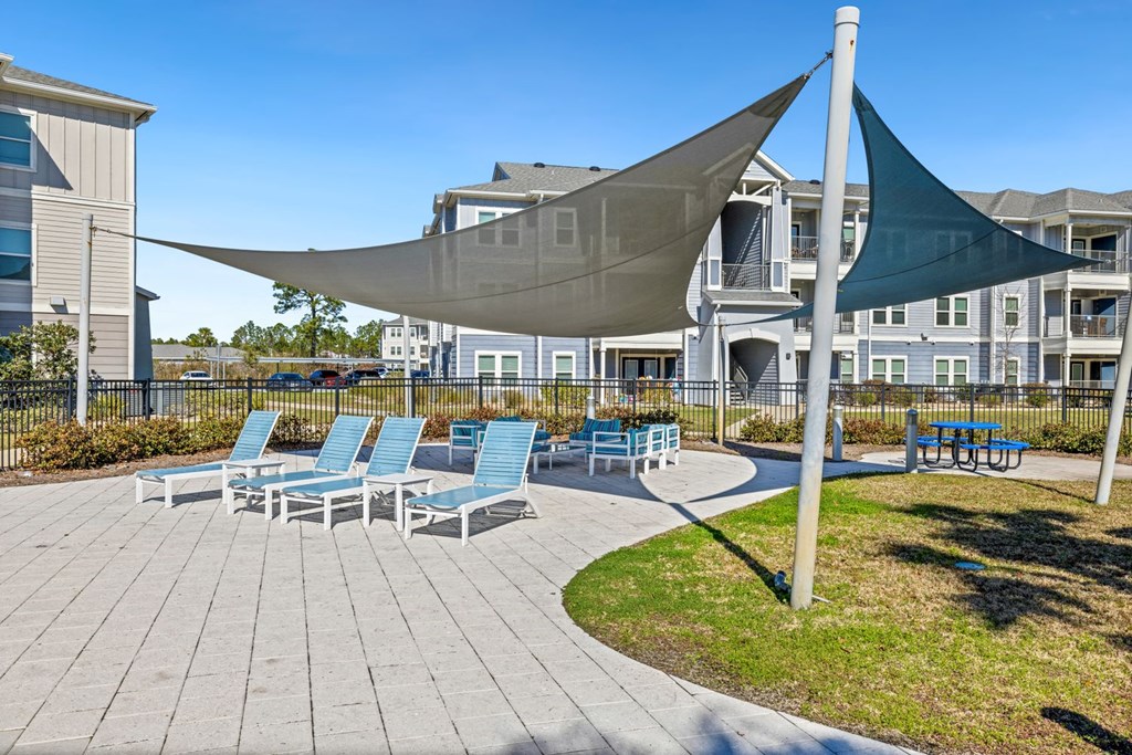 A patio with blue chairs and a white umbrella.