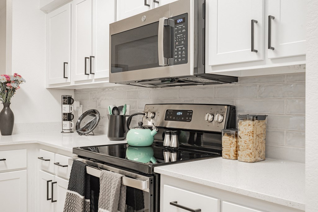a kitchen with white cabinets and a stove and a microwave
