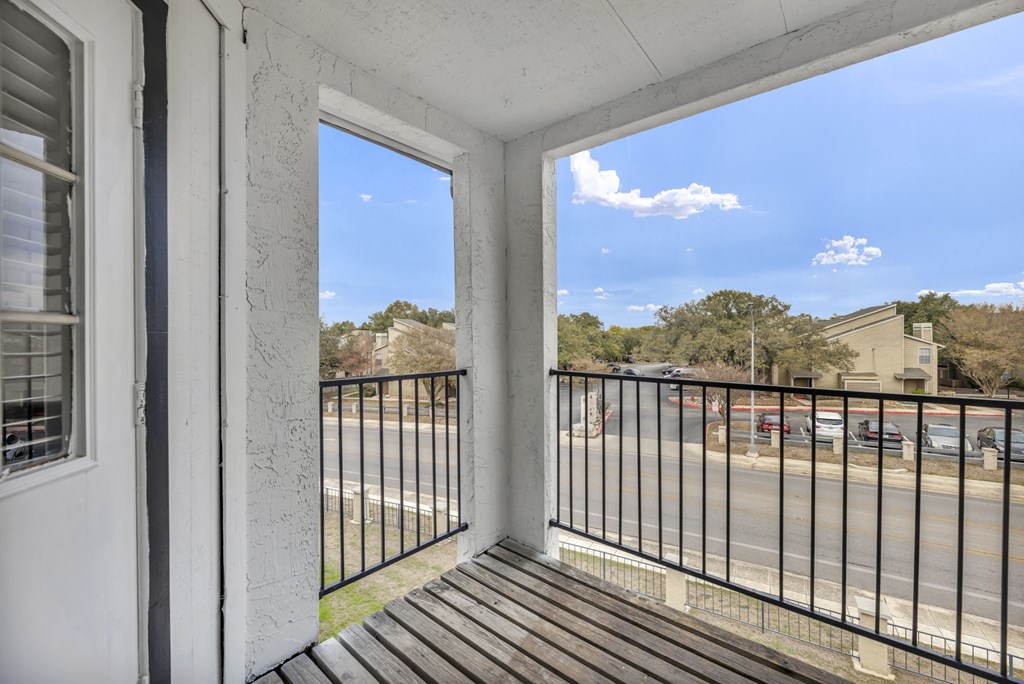 A balcony with a black railing and a view of a street.