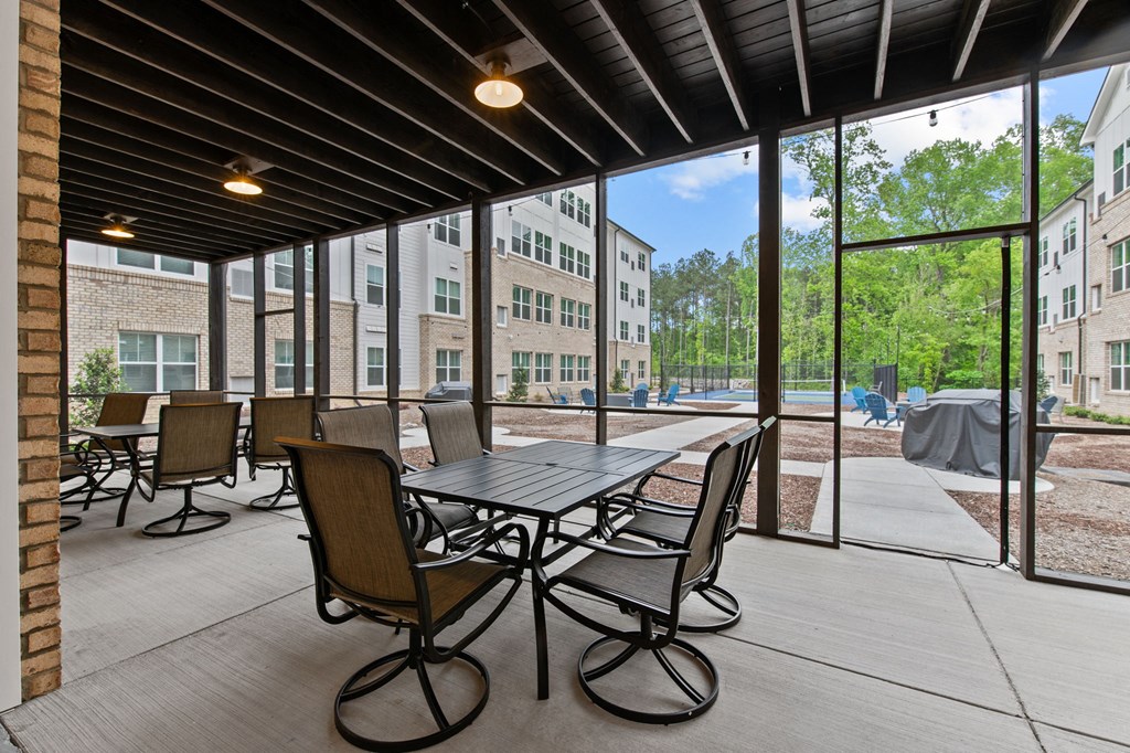 clubhouse patio with tables and chairs and large windows with buildings in the background