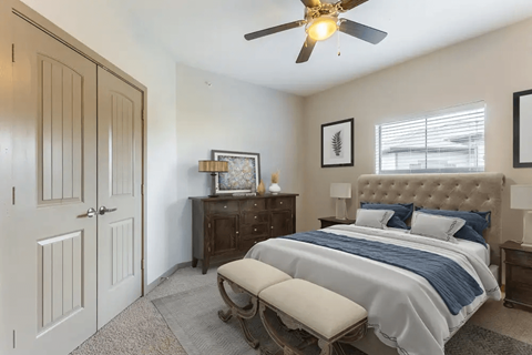 A bedroom with a bed, dresser, and a ceiling fan.