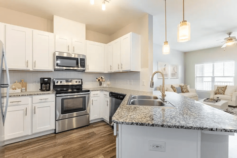 A kitchen with white cabinets and a granite countertop.