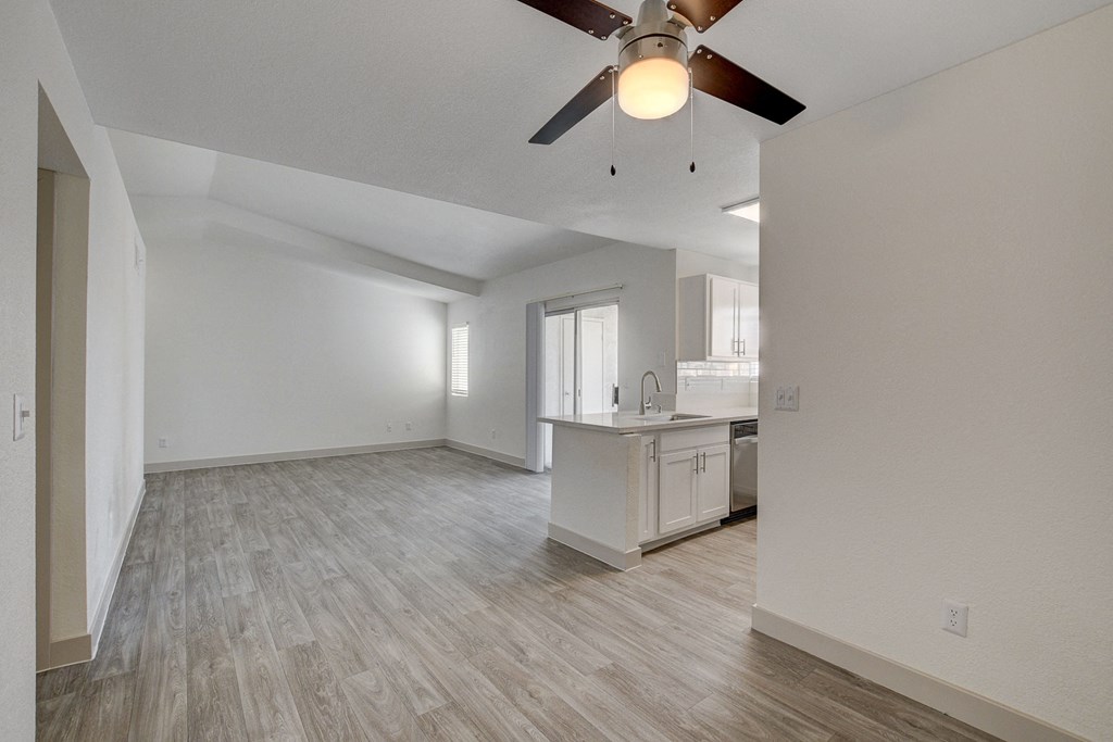 an empty living room with a ceiling fan