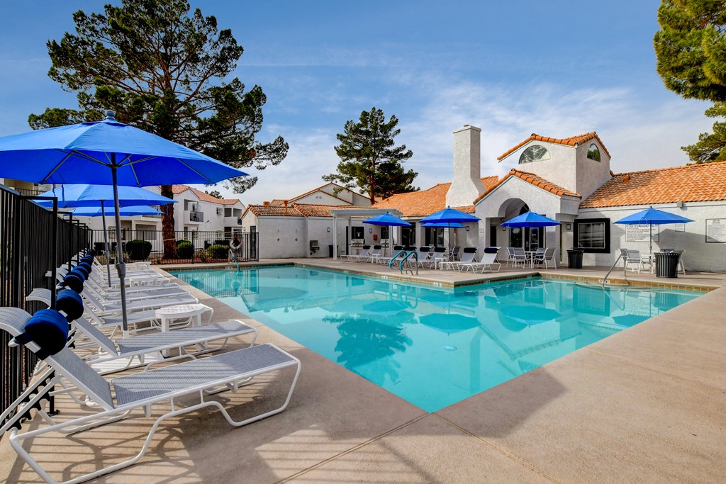 a swimming pool with lounge chairs and umbrellas