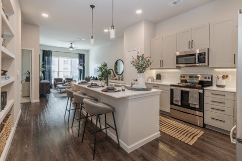 an open kitchen and living room with an island and stools