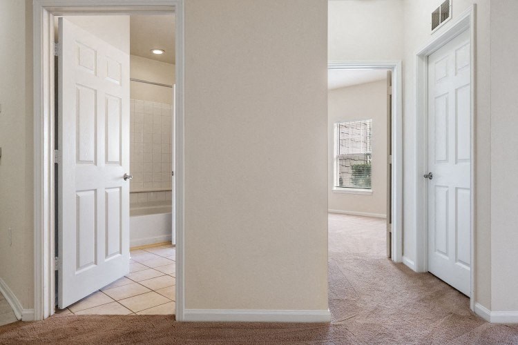 a hallway with a door open to a bathroom and a closet
