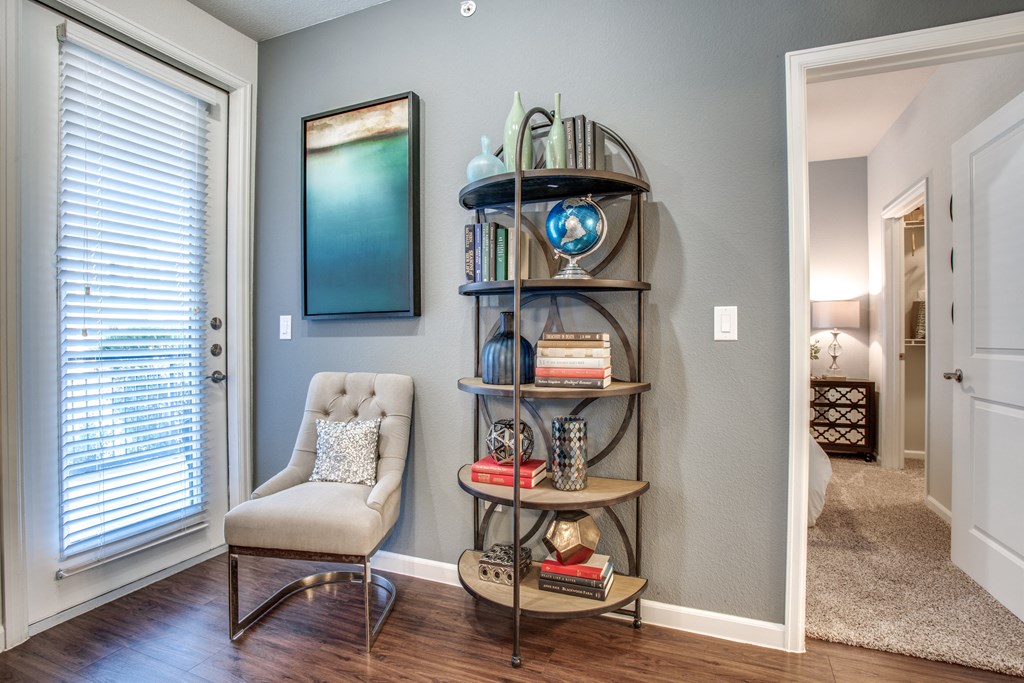 a living room with a chair and a shelf with books