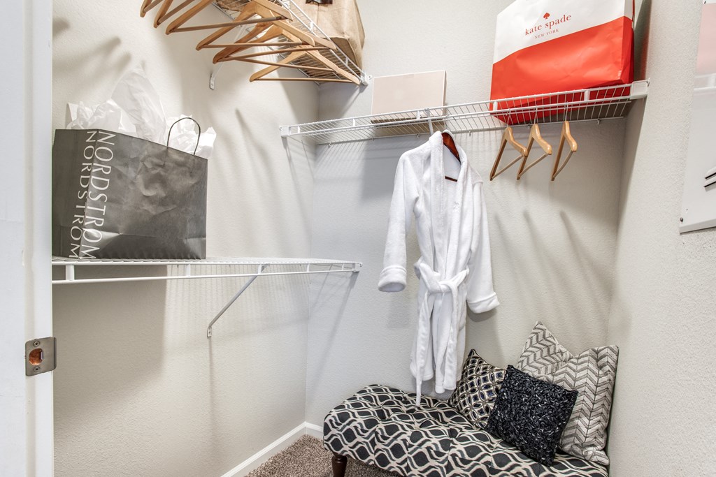 a dressing room with a chair and a closet with clothes