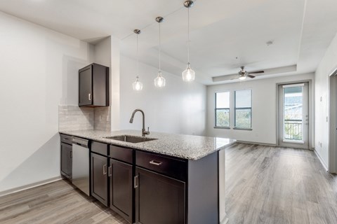 A kitchen with dark brown cabinets and a granite countertop.