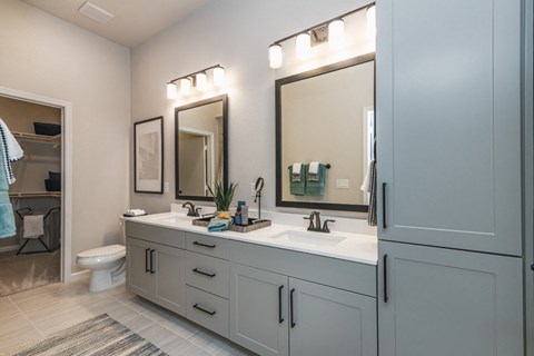 a bathroom with a sink and two mirrors and a toilet