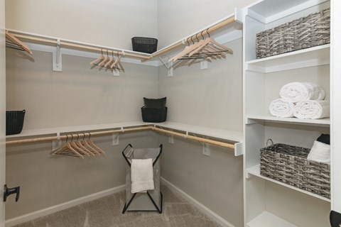 a walk in closet with a chair and shelves with folded towels