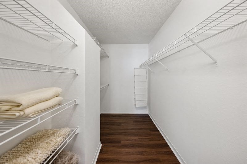 a walk in closet with white closets and white walls