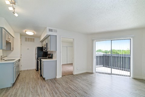 an open kitchen and living room with a sliding glass door to a balcony