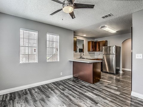 A kitchen with a wooden floor and a stainless steel refrigerator.