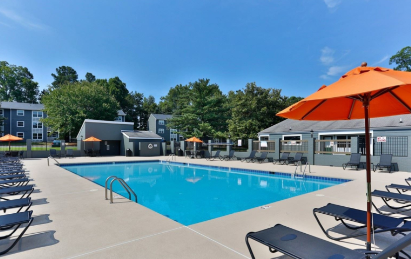 a swimming pool with umbrellas and chaise lounge chairs in front of a building
