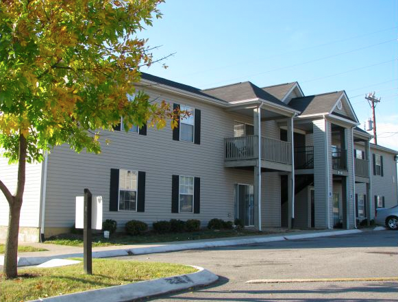 a street view of an apartment complex with a tree in the foreground