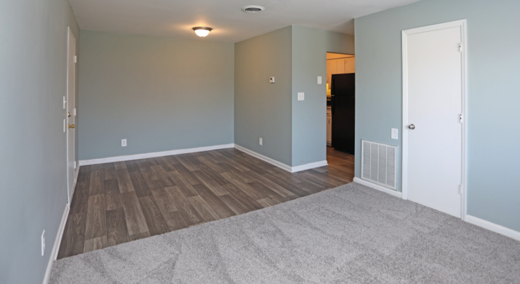 a living room with a carpet and a door to a hallway