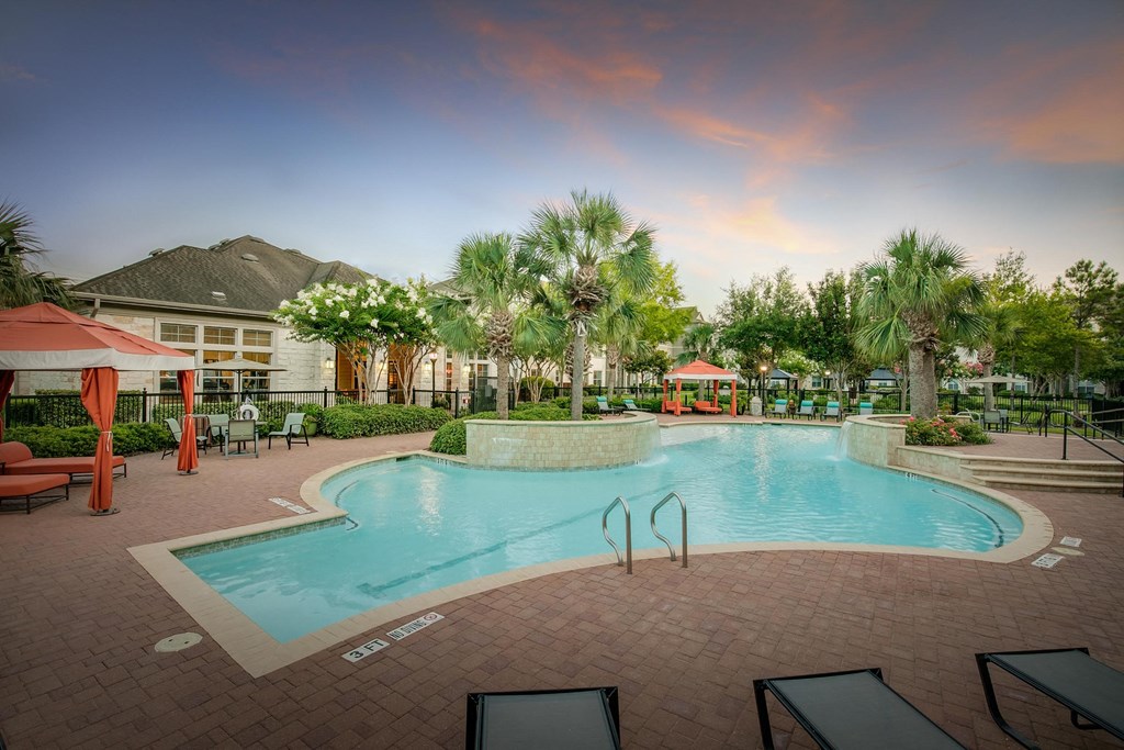 a resort style pool with lounge chairs and umbrellas