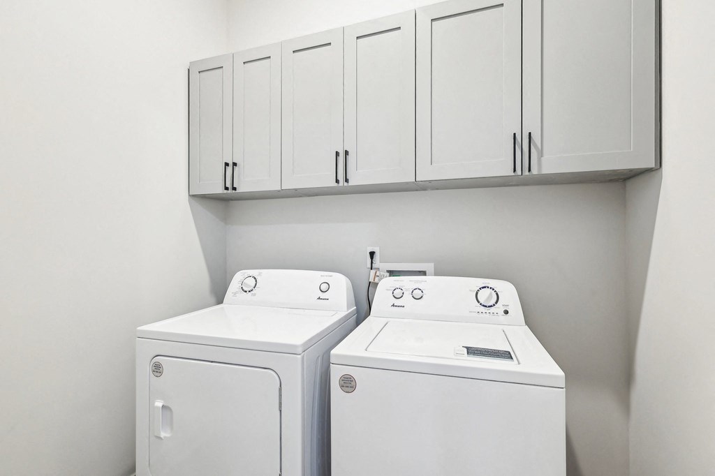 Two white washing machines in a laundry room.
