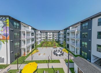 A sunny day at a modern apartment complex with a courtyard in the center.