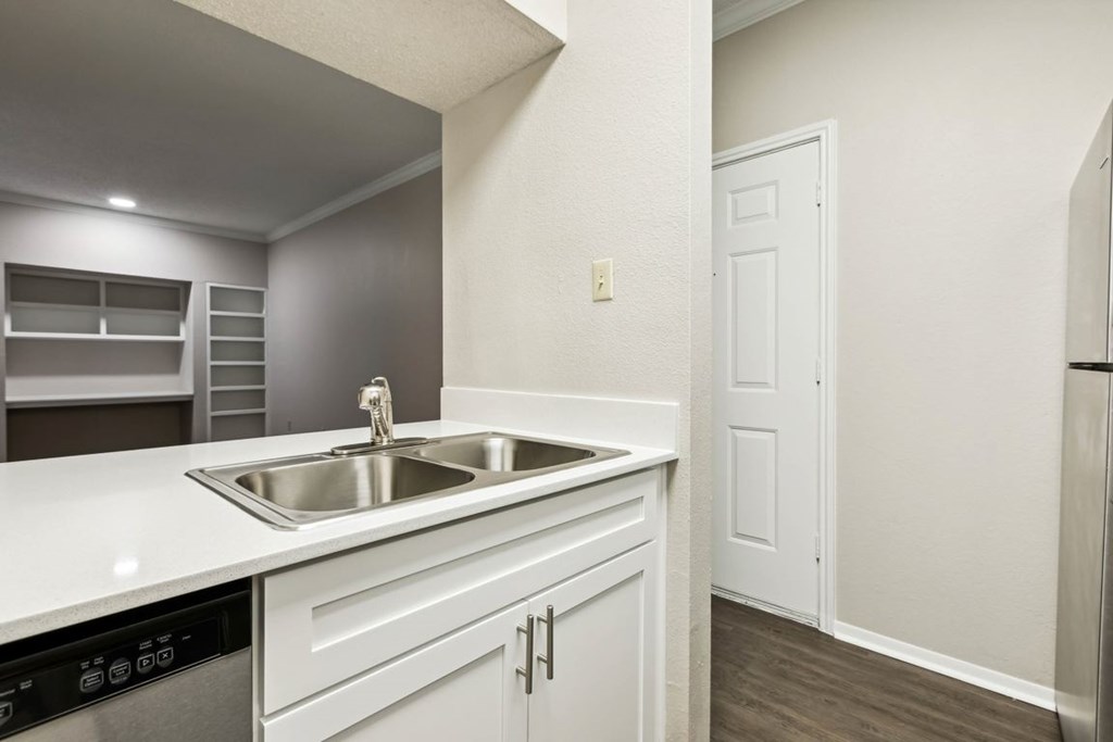 A kitchen with white cabinets and a stainless steel sink.