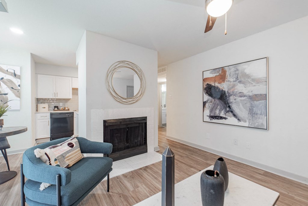 A living room with a fireplace, a blue chair, and a painting on the wall.