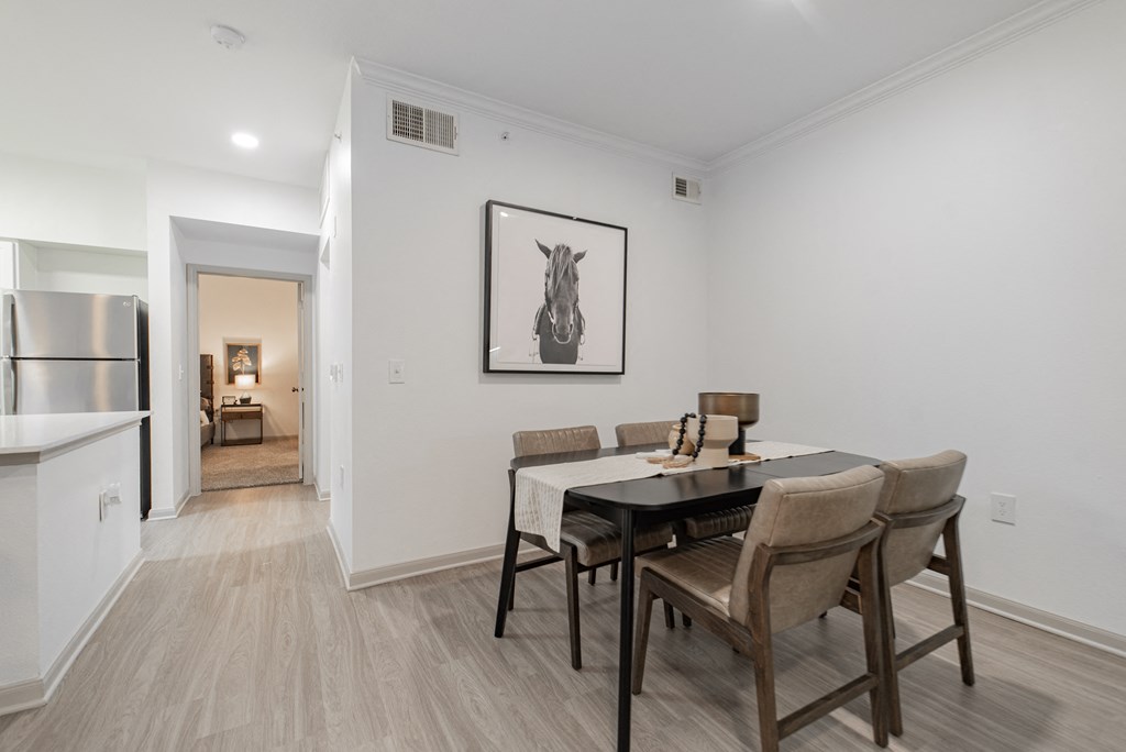 a dining room with a table and chairs and a kitchen with a refrigerator
