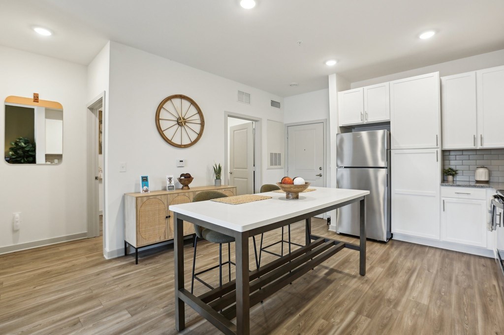 A modern kitchen with a wooden table and stainless steel appliances.