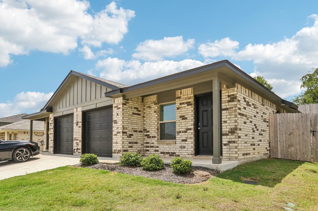 A house with a black garage door and a grey car parked in front.