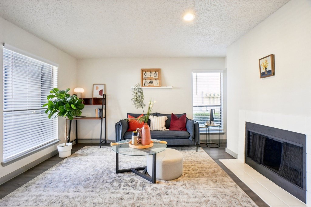 A living room with a grey couch, a glass coffee table, and a fireplace.
