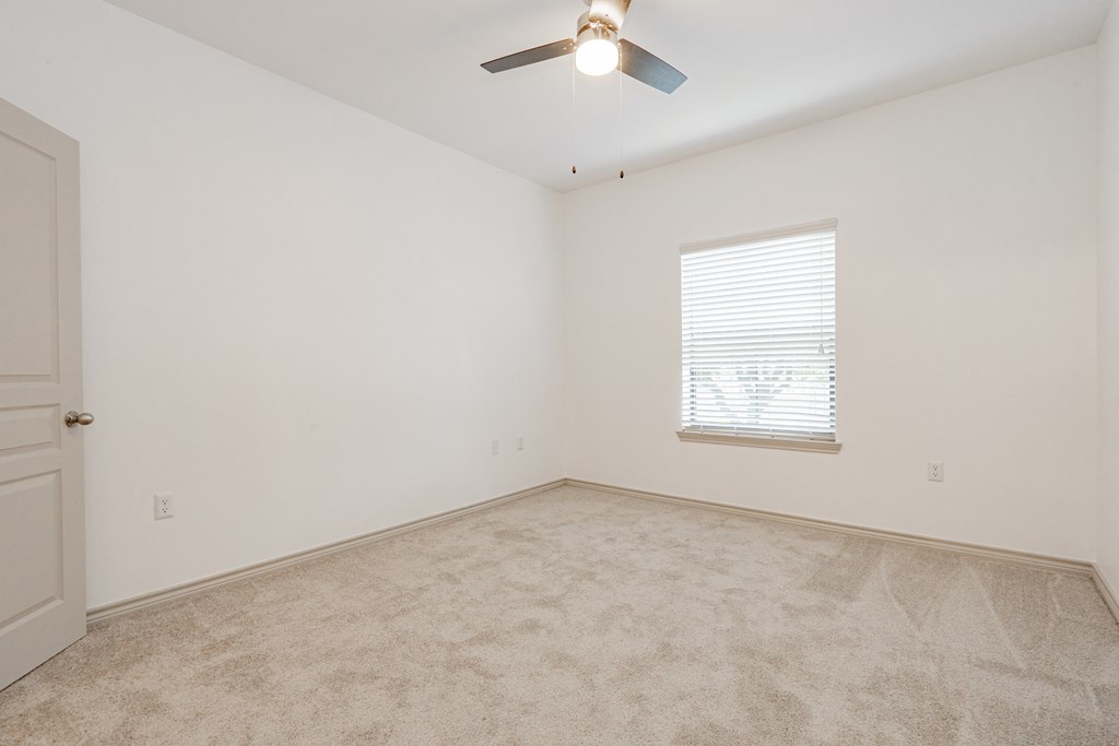 an empty room with a ceiling fan and a window