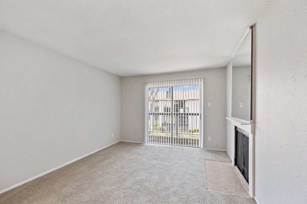 a spacious living room with a fireplace and a door to a balcony