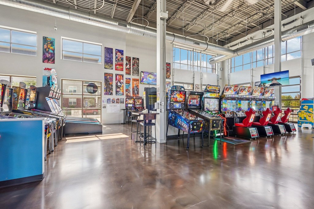 A row of arcade games are lined up in a large room.