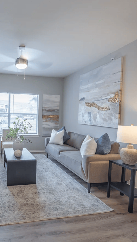 A living room with a grey couch, a coffee table, and a large painting on the wall.