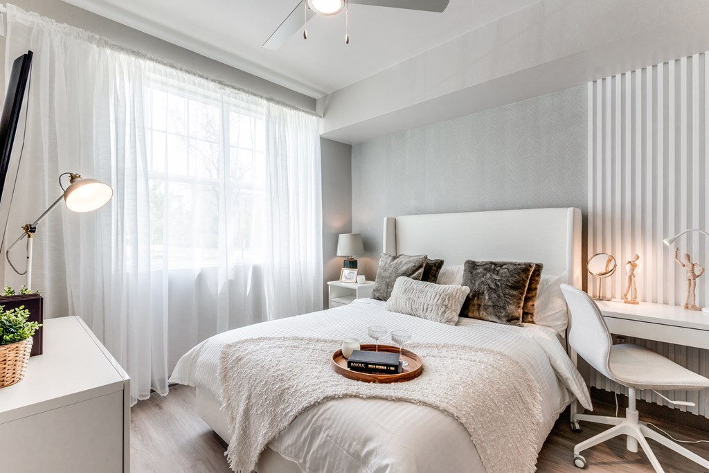 A bedroom with a large bed and a window with curtains.