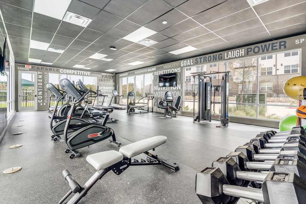 A gym with a variety of equipment including weights and a rowing machine.
