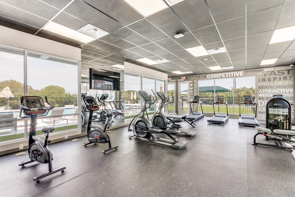 A gym with a variety of exercise equipment including treadmills, stationary bikes, and weight machines.