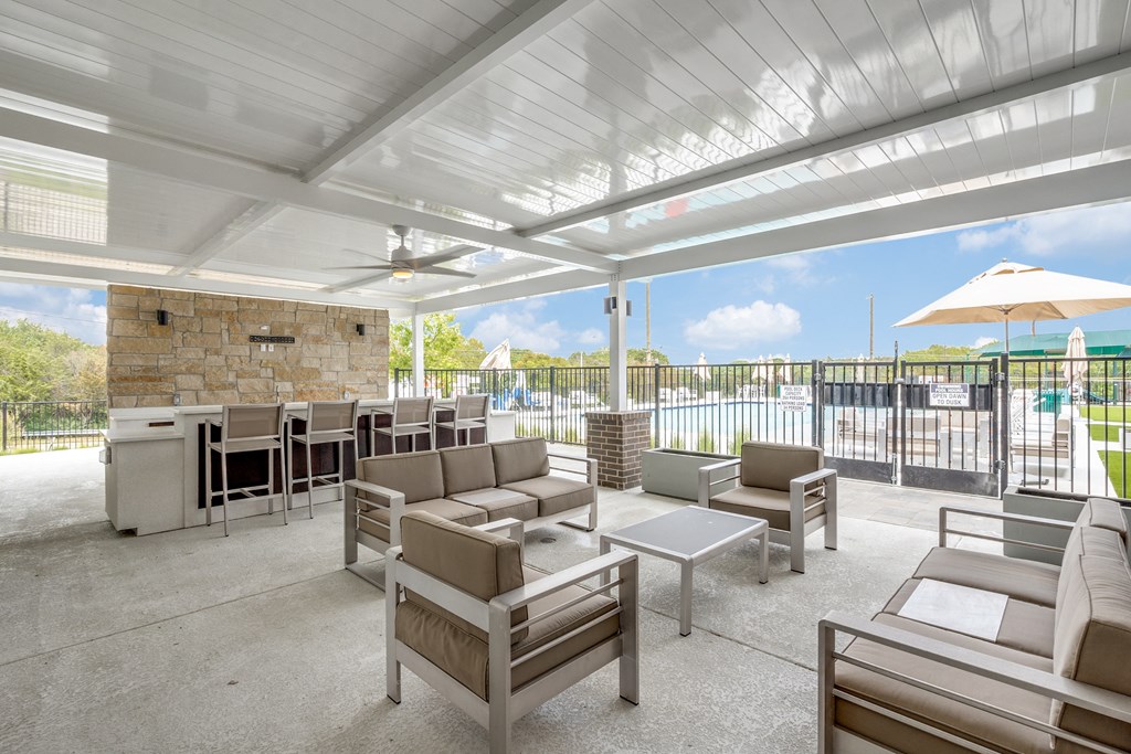 a patio with couches and chairs and a pool in the background