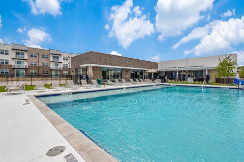 A large swimming pool in front of a building with a sunny sky.